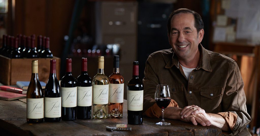 man sitting at table with wine bottles in front of him