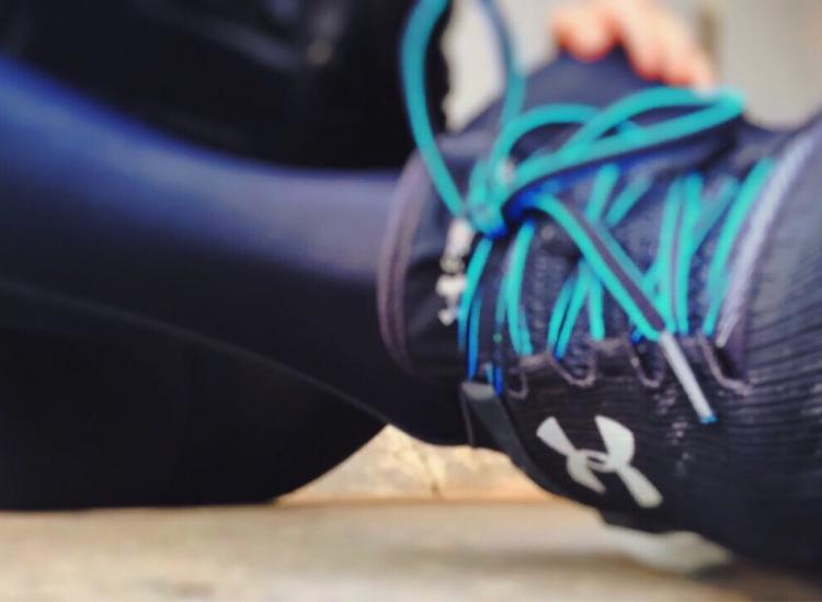 a black running shoe is shown with blue laces