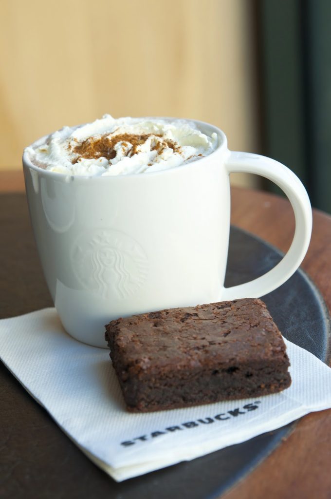 Cup of coffee with a brownies beside it on a table